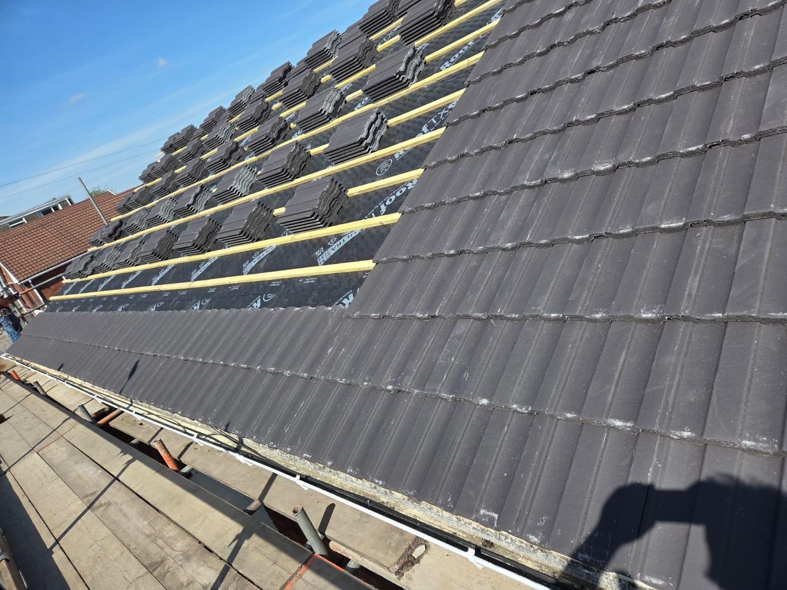 New tiles being laid over fresh membrane and battens during a re-roof in Heolgerrig