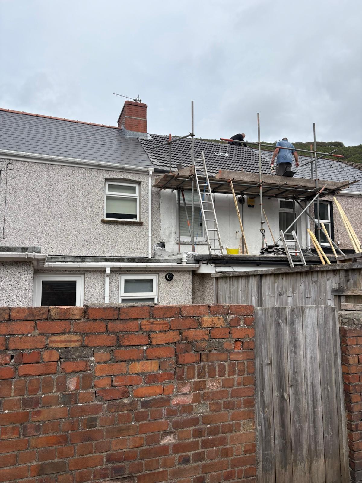 K Williams Roofing team laying new grey roof tiles from scaffolding in Ebbw Vale